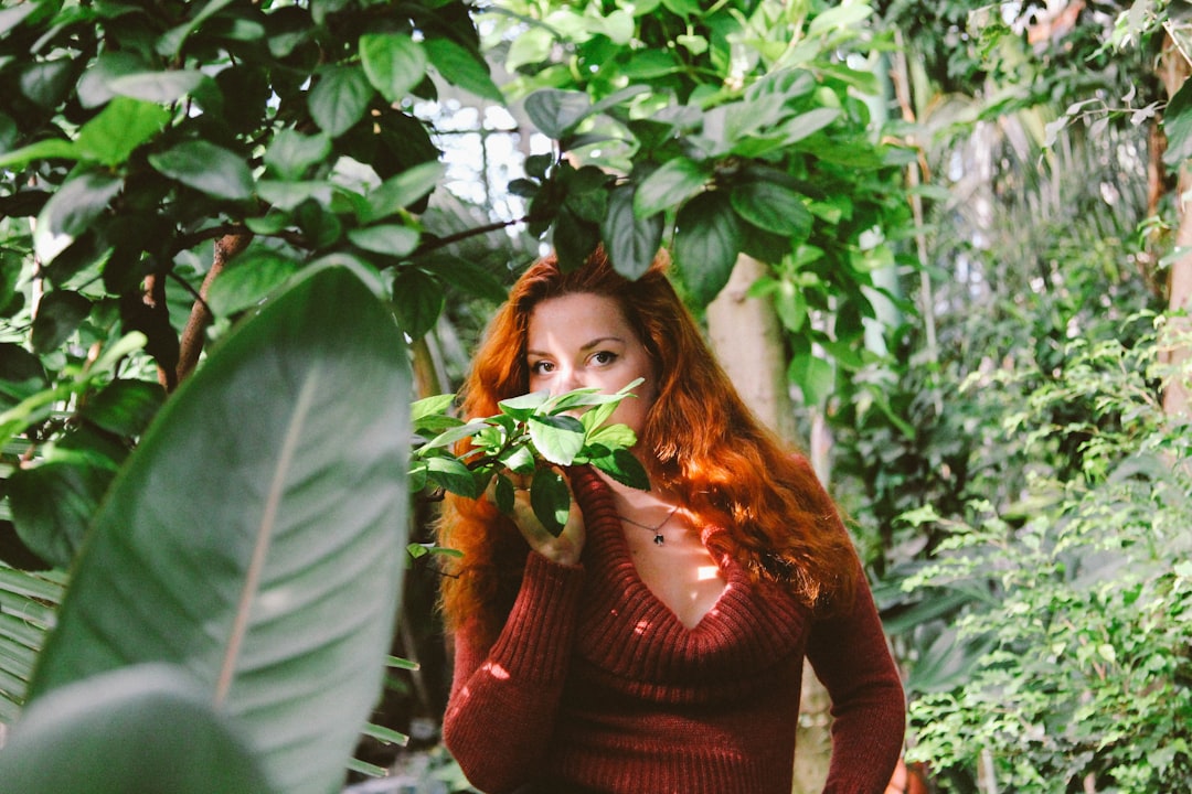 a woman with red hair is holding a plant